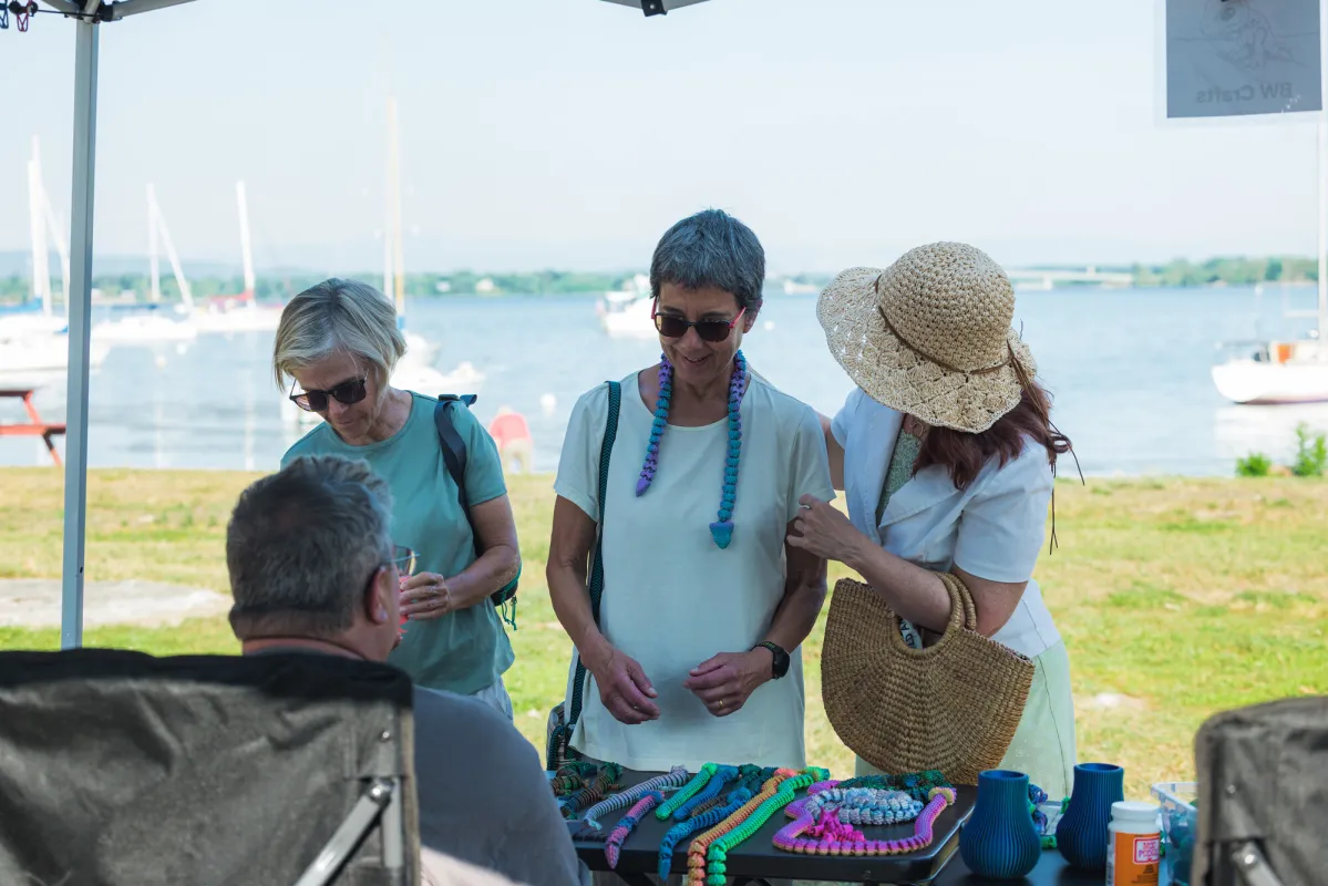 Three women talk with a merchant at a farmers' market.