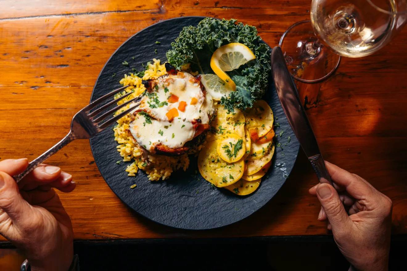 A woman dines on a plate of eggs and potatoes.