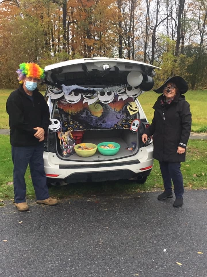two people handing out candy from a trunk of a vehicle