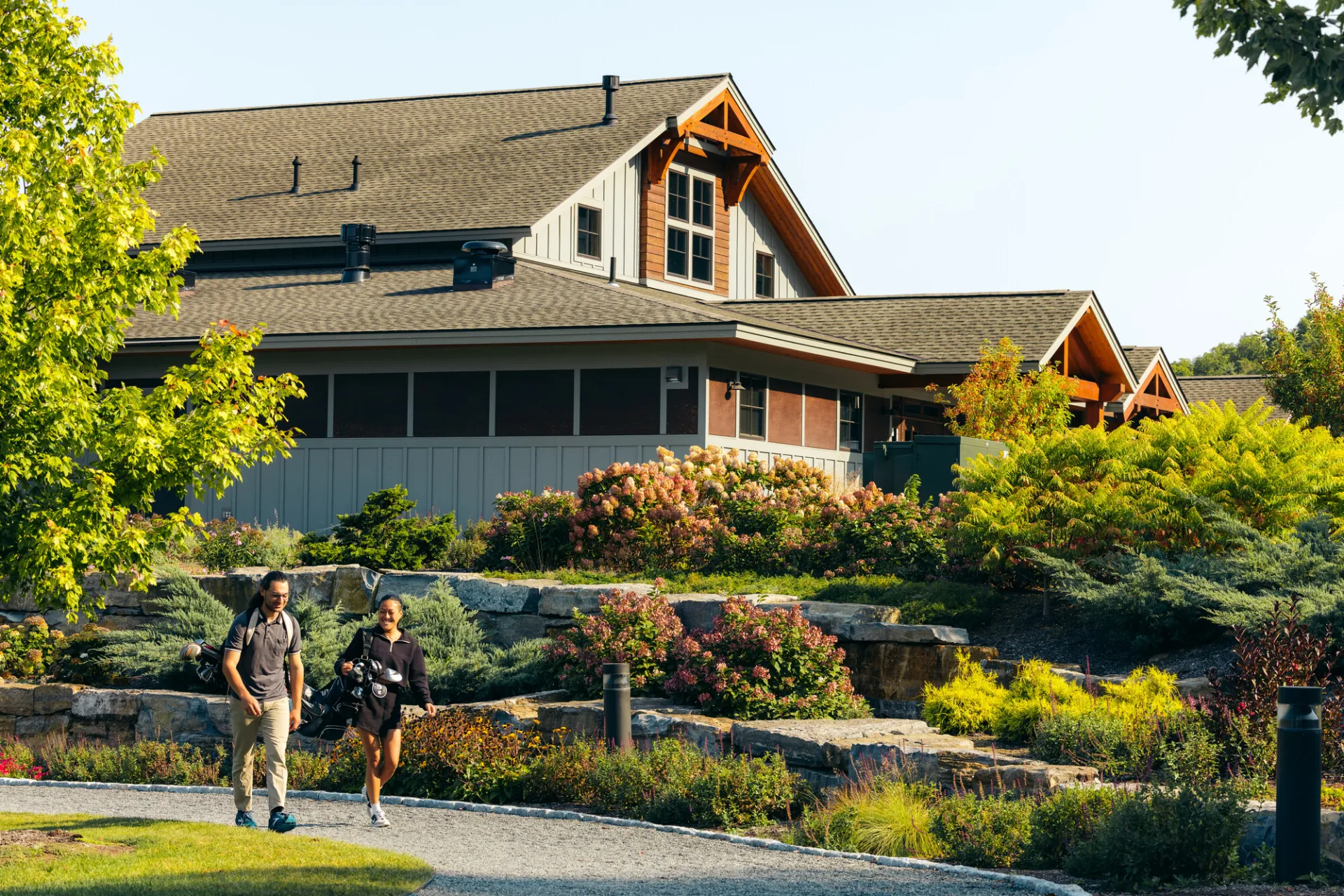 A man and woman walk past a floral golf club house. 