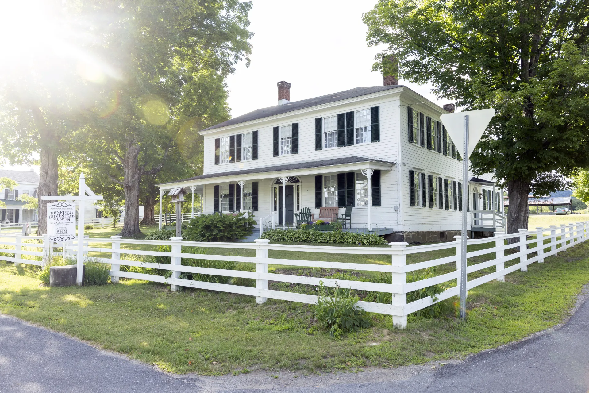 A white building with black trim and a white split rail fence.