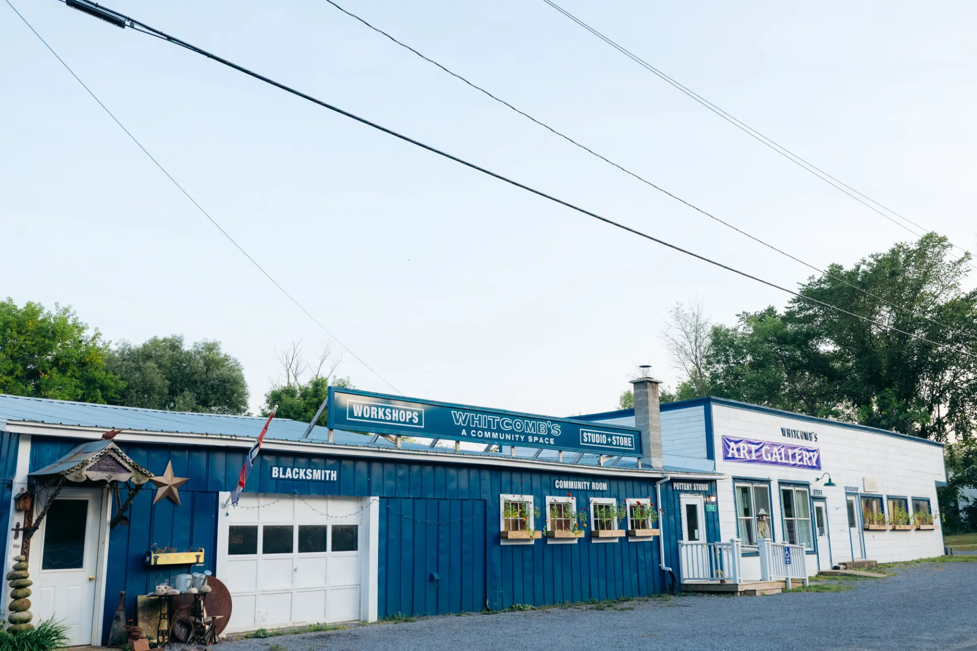 A blue garage attached to a white storefront for an art gallery and event space.