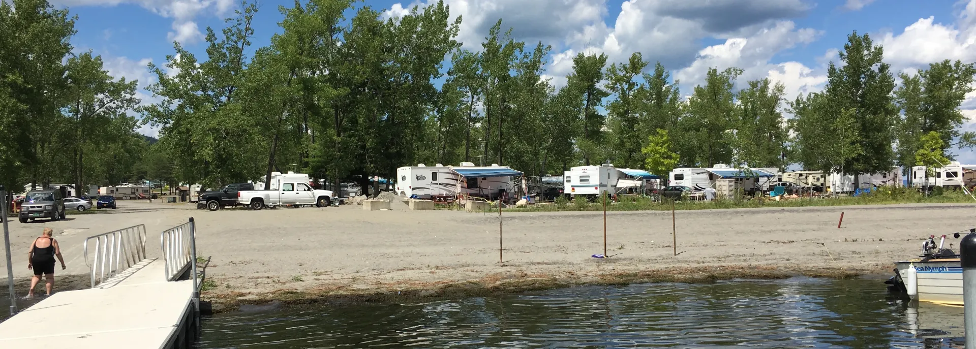 RVs parked right by the sandy shores of a lake.