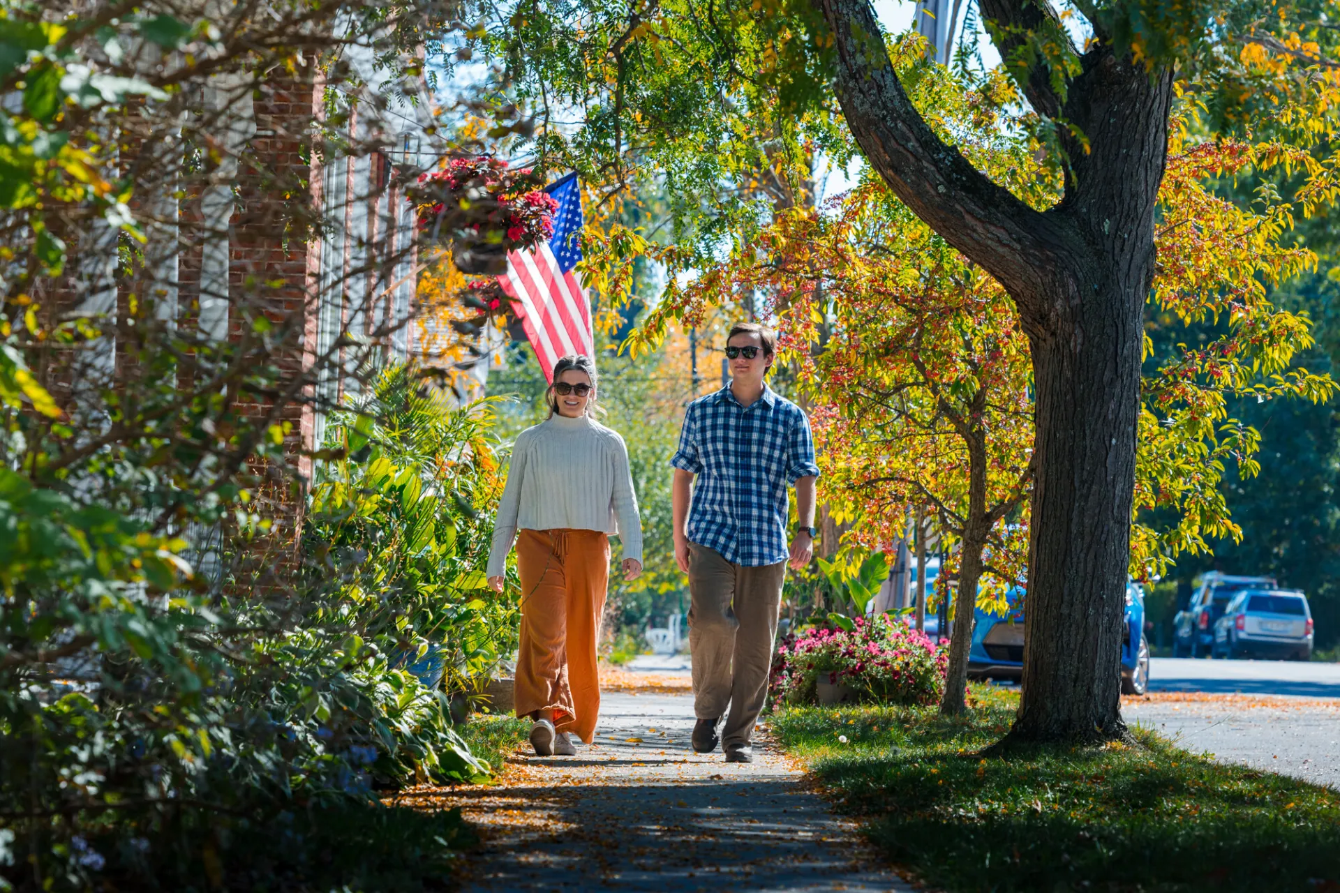 A man and woman walk down a street in a small town in fall.