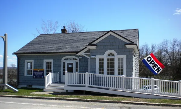 The entry to the grey building with white trim with entry ramp of the former bridge toll house, now visitors center.