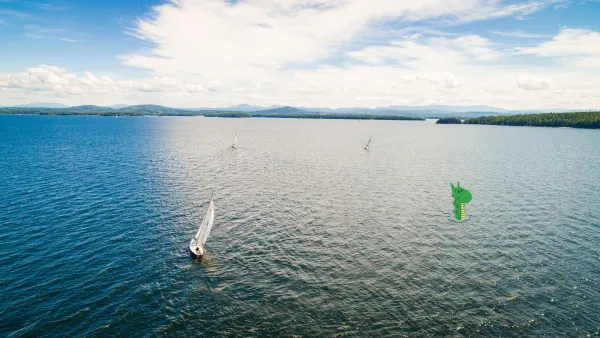 An aerial view of three sailboats on a large lake. A cartoon lake monster peeks out of the water on the right.