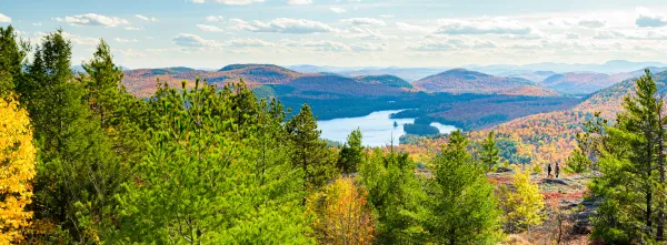 A large pond nestled among colorful fall mountains. 