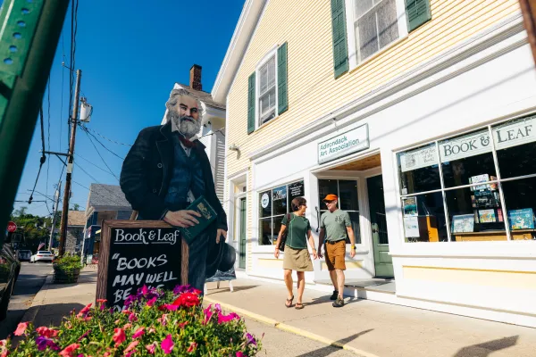 A man and woman walk out of an art shop in a small town.