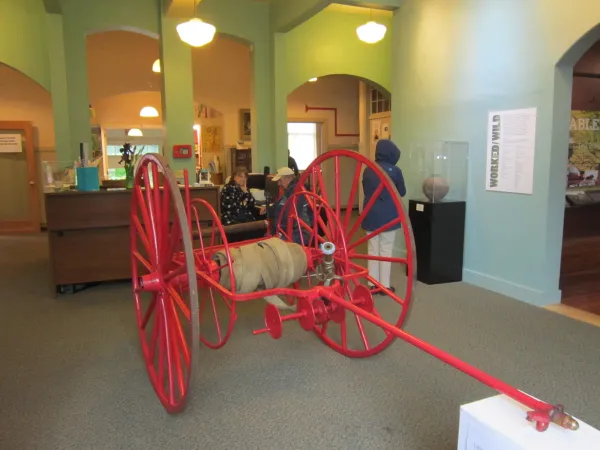 A red fire hose reel on large wagon wheels.