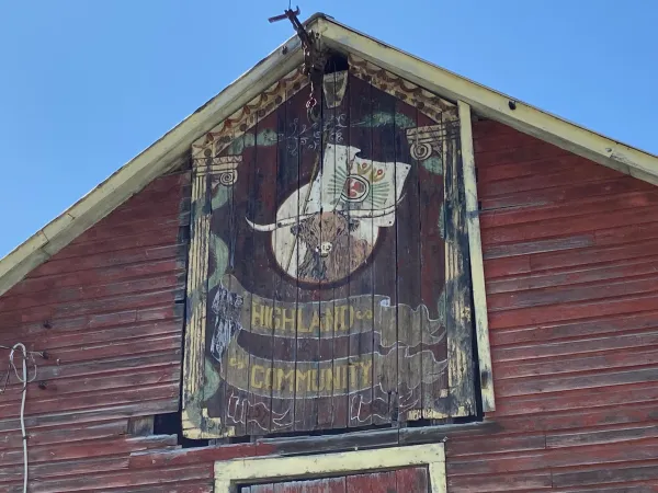 A barn with a Highland cow sign above the doors.