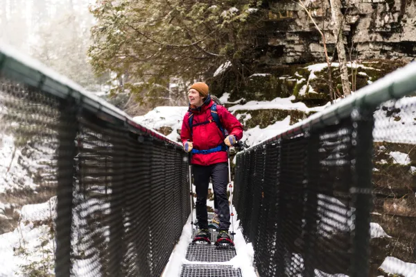 A man looks out from a metal bridge in winter. 