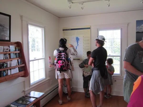 A family views the map of Lake Champlain that is hung on the wall of the visitors center.