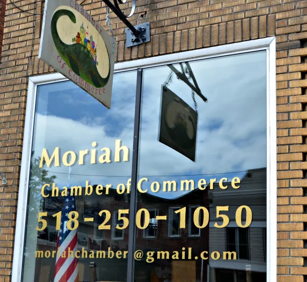 A brick building with a large glass window with Moriah Chamber of Commerce 518-250-1050.