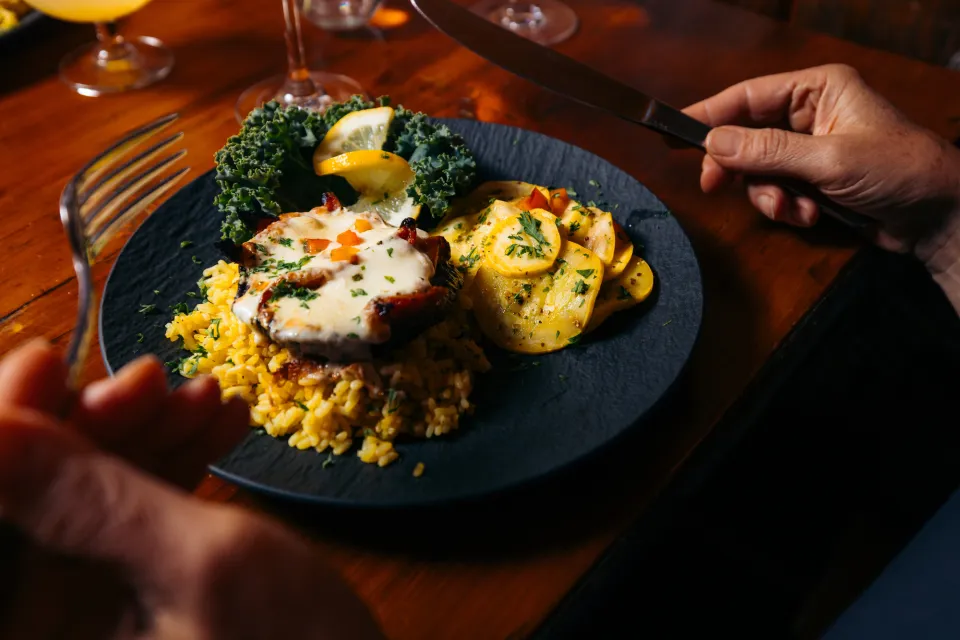 A woman dines on a plate of eggplant parmesan and rice.